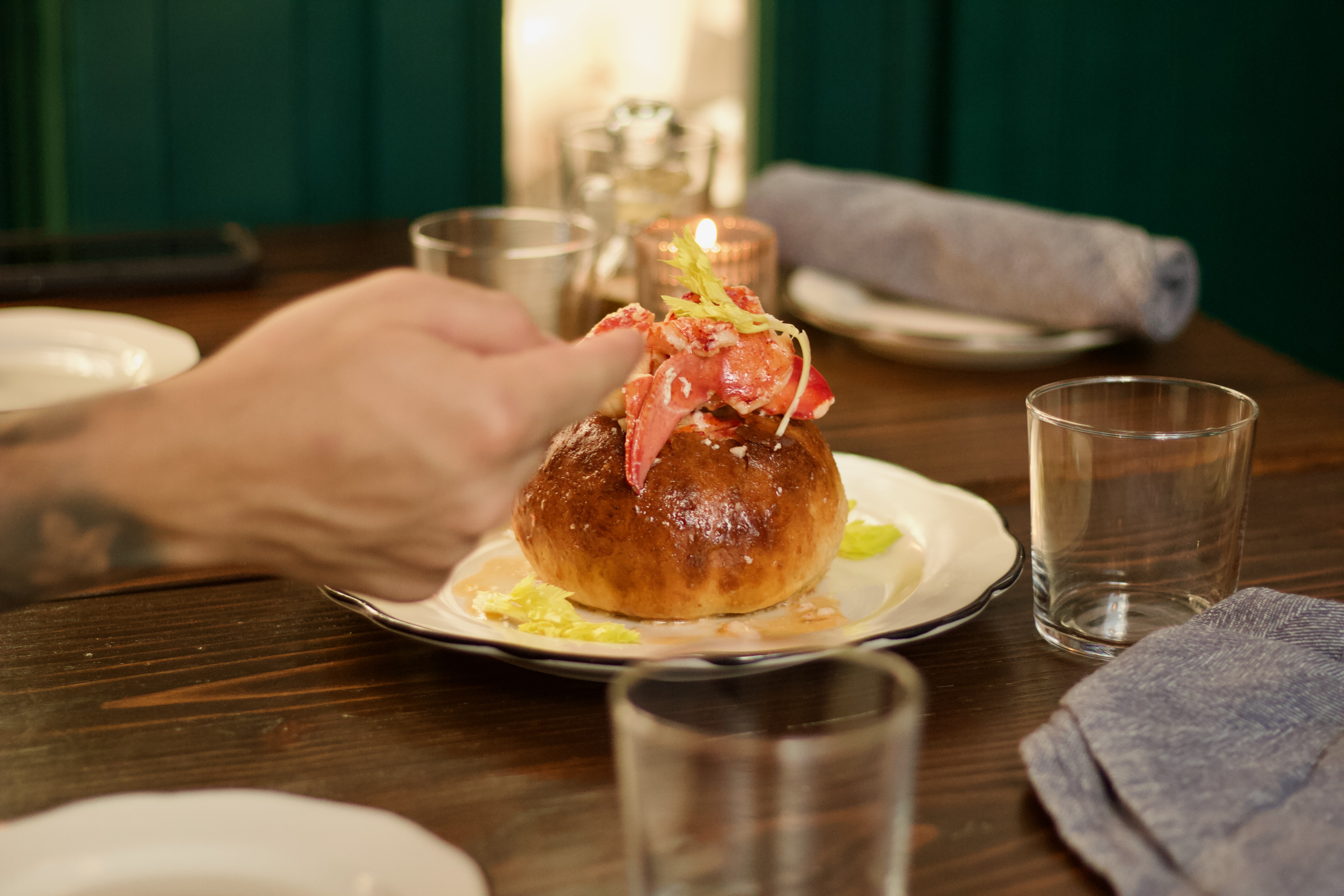 Lobster roll on brioche bun, candlelit table