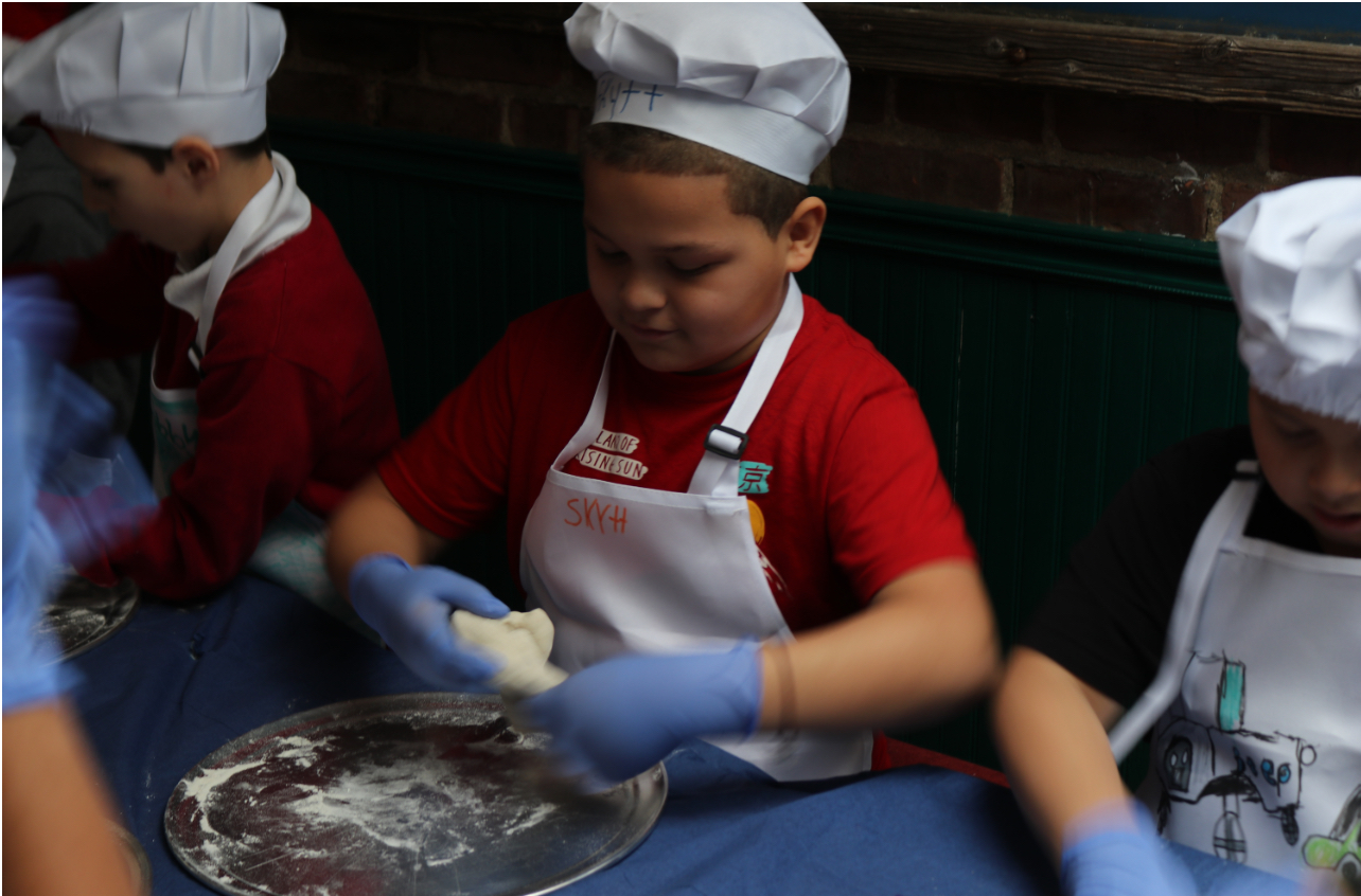 Kids in chef hats making pizza dough — pizza class
